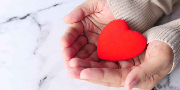 CITI-perguntas-doaçao-ovulos mãos de mulher recebendo coração vermelho de borracha representando óvulos doados com amor